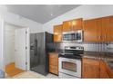 Functional kitchen featuring stainless steel appliances and wood cabinetry, with an adjacent door at 3238 Cloverplace Dr, Palm Harbor, FL 34684