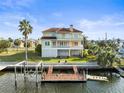 Stunning waterfront home with multi-level decks, boat dock, lush landscaping and mature palm trees at 3447 Flamingo Blvd, Hernando Beach, FL 34607
