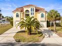 Stunning two-story home with a tile roof, a well-manicured lawn, and a palm tree in the front yard at 3447 Flamingo Blvd, Hernando Beach, FL 34607