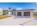 Bright exterior with a white brick facade, blue front door, long driveway, and attached two-car garage at 3908 Wahoo Se Dr, St Petersburg, FL 33705