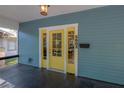 Close-up of the yellow front door framed by white trim, providing a pop of color and inviting entry at 5603 N Taliaferro Ave, Tampa, FL 33604