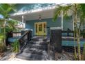 Inviting front porch featuring a bright yellow front door with glass panels and sleek, dark painted steps at 5603 N Taliaferro Ave, Tampa, FL 33604