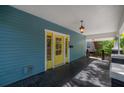 Spacious front porch with a vibrant yellow door and side windows, offering a bright and welcoming entrance at 5603 N Taliaferro Ave, Tampa, FL 33604