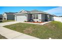 Single-story home with a gray exterior, two car garage, tidy landscaping and a concrete driveway and walkway at 6863 Hanworth Ln, Zephyrhills, FL 33541