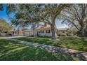 Landscaped front yard of the home, complete with mature trees and a sidewalk at 1028 Rosetree Ln, Tarpon Springs, FL 34689