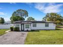 Front exterior of the house with black trim, white walls, and lush, green landscaping at 1054 W Baffin Dr, Venice, FL 34293