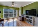 Bright living room with a ceiling fan, hardwood floors, a TV, and large windows with plantation shutters at 1216 S Missouri Ave # 225, Clearwater, FL 33756