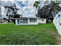 A modest backyard with an enclosed porch area and a spacious lawn at 1620 Dander Dr, Holiday, FL 34690