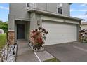 Close up exterior of home with gray door, two car garage, and small rocks with plants at 7842 Carriage Pointe Dr, Gibsonton, FL 33534