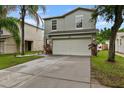 Daytime view of a gray two-story home featuring a well-maintained lawn and a two-car garage at 7842 Carriage Pointe Dr, Gibsonton, FL 33534
