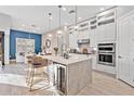 Bright open-concept kitchen with a large marble island, white cabinetry, and stainless steel appliances at 809 Seascape Pl, Sarasota, FL 34240