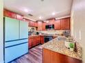 Well-equipped kitchen with granite countertops, dark wood cabinets, and stainless steel appliances at 9873 Trumpet Vine Loop, Trinity, FL 34655