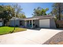 Inviting home boasts a large driveway, attached garage and covered porch with cozy blue chairs at 11980 Valencia Ct, Seminole, FL 33772