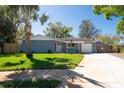 Cozy home with lush green lawn, mature trees, covered porch with blue chairs and a single car garage at 11980 Valencia Ct, Seminole, FL 33772
