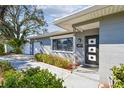 Beautifully landscaped home with manicured bushes and a covered entryway with a modern front door at 1269 80Th N Ave, St Petersburg, FL 33702