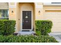 Close-up of the front door framed by lush greenery, decorative sconces, and a welcoming 'home' doormat at 15425 Long Cypress Dr, Ruskin, FL 33573