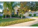 Well-maintained home with a manicured lawn, palm trees, and an attached two-car garage in a sunny setting at 15425 Long Cypress Dr, Ruskin, FL 33573