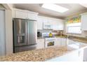 Bright kitchen with stainless steel refrigerator, white cabinets, and granite countertops at 6025 Shore S Blvd # 611, Gulfport, FL 33707