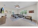 Comfortable living room with a large sectional, ceiling fan, and natural light from large windows at 7133 Hatpin Loop, Wesley Chapel, FL 33545