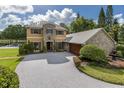 Stunning home with lush landscaping, a circular driveway, and a stone-accented garage with a fountain at 8711 Brooke Angela Dr, Odessa, FL 33556