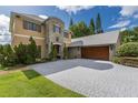 Home with a gray brick driveway and a large garage with wooden doors at 8711 Brooke Angela Dr, Odessa, FL 33556