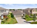 Residential home showcasing its large driveway, neutral exterior, and well-kept lawn within a Gathering-friendly neighborhood at 9412 Lemon Drop Loop, Ruskin, FL 33573