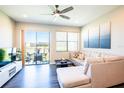 Bright living room with wood floors, ceiling fan, sliding door to patio, and comfortable sectional sofa at 11648 Crowned Sparrow Ln, Tampa, FL 33626