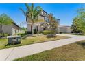 Attractive home exterior featuring a landscaped yard, mature trees, and a paved sidewalk at 14618 Scottburgh Glen Dr, Wimauma, FL 33598