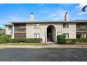 A two-story condominium building with a stucco exterior, chimneys, and mature landscaping near the entrance at 2087 Hunters Glen Dr # 126, Dunedin, FL 34698
