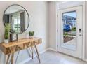 Bright foyer with tile flooring, a console table with mirror, and front door with sidelight at 2944 Gardiner Ln, Zephyrhills, FL 33541