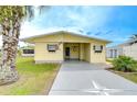 Inviting yellow home with attached carport, landscaped yard, and charming curb appeal at 35246 Tiffani Ct, Zephyrhills, FL 33541