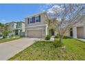 Two-story home featuring a two car garage, neutral paint, and tidy landscaping under a blue sky at 10967 Carlton Fields Dr, Riverview, FL 33579