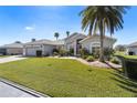 Well-maintained single-story home featuring lush lawn and a two-car garage with mature landscaping at 11013 Moshie Ln, San Antonio, FL 33576