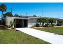 Inviting home exterior with a bright white driveway, lush lawn, and mature trees under a clear blue sky at 1503 Council Dr, Sun City Center, FL 33573