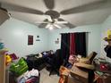 A cluttered bedroom with a ceiling fan and a few decorations on the light-blue walls at 3111 W Spruce St, Tampa, FL 33607