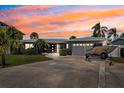 Charming single-story home with a driveway, tropical landscaping, and a beautiful sunset at 3906 Versailles Dr, Tampa, FL 33634