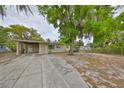 Inviting single-story home with a convenient carport and a picturesque front yard adorned with mature trees at 434 Pevetty Dr, Plant City, FL 33563
