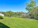 Large backyard featuring green grass, a black metal fence, and scenic views of a pond and wooded area at 5016 Bella Armonia Cir, Wimauma, FL 33598