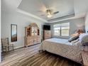 Comfortable main bedroom features a tray ceiling, wood floors, and an expansive window for natural light at 5016 Bella Armonia Cir, Wimauma, FL 33598
