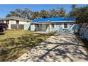 Single-story home with bright blue tarp on the roof, a driveway, and a partially fenced yard with mature trees at 6708 S Faul St, Tampa, FL 33616