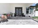 Inviting front porch with tiled flooring, stylish seating, and a modern front door with glass panels at 7403 Edgemere Rd, Tampa, FL 33625