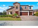 Two story home featuring stone accents, a three-car garage, and well maintained landscaping at 13103 Wildflower Meadow Dr, Riverview, FL 33579