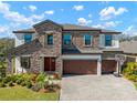 Beautiful two-story home showcasing stone accents, a three-car garage and manicured lawn at 13103 Wildflower Meadow Dr, Riverview, FL 33579