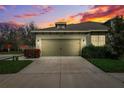 Charming single-story home featuring a two-car garage during a colorful sunset at 1467 Twin Villas Way, Dunedin, FL 34698