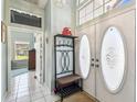 Bright entryway with decorative front doors, coat rack, and tiled floor, offering a welcoming ambiance at 18739 Bascomb Ln, Hudson, FL 34667