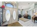 Airy foyer featuring decorative front doors, chandelier, and a view of the piano and office area at 18739 Bascomb Ln, Hudson, FL 34667