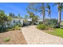 Single story home with a brick driveway, lush landscaping, and blue shutters at 2401 S Shore Se Dr, St Petersburg, FL 33705