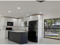 Stylish kitchen with a dark island, white cabinets, and modern black appliances at 6125 Liberty Ave, Temple Terrace, FL 33617