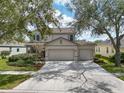 A quaint two-story home with a three-car garage, beautiful landscaping, and an expansive driveway at 6308 Bridgevista Dr, Lithia, FL 33547