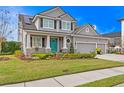 Charming gray home with a bright blue front door, stone accents, and a lush, colorful garden at 7820 Marsh Pointe Dr, Tampa, FL 33635